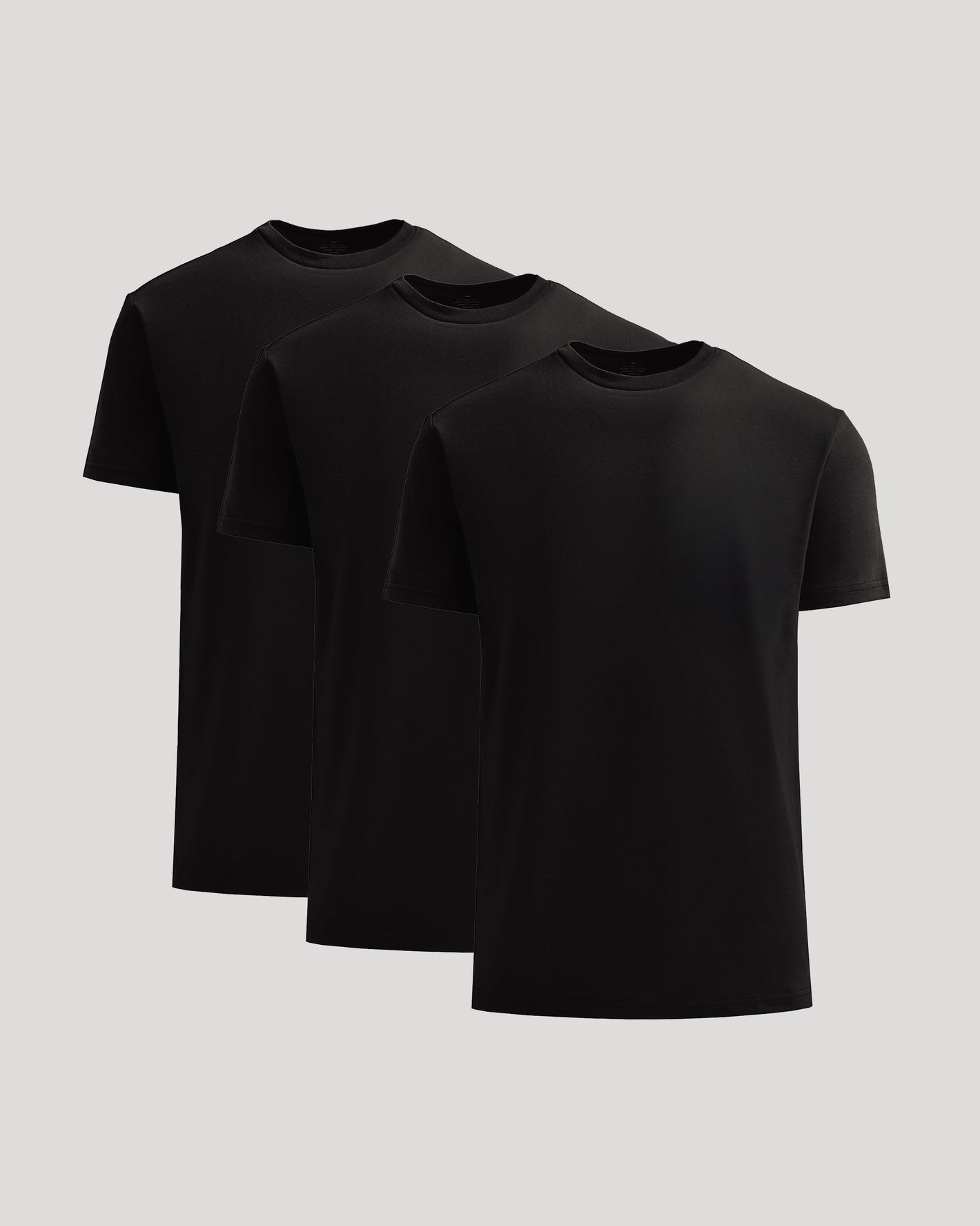Three black t-shirts stacked on a light gray background