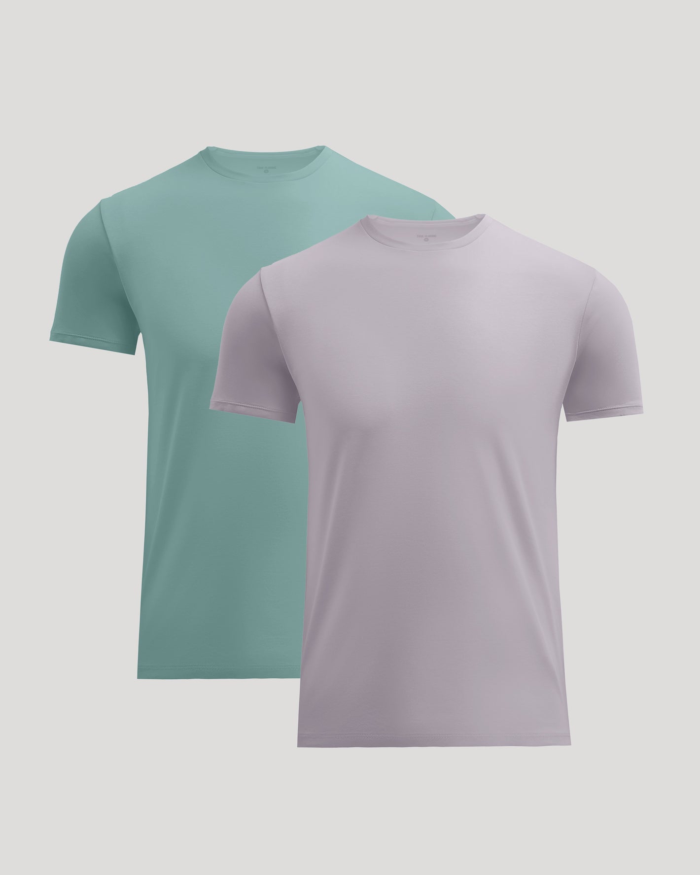 Two short-sleeve crew-neck t-shirts shown on a light gray background, one in mint green and one in pale lavender, with the lavender shirt in front.