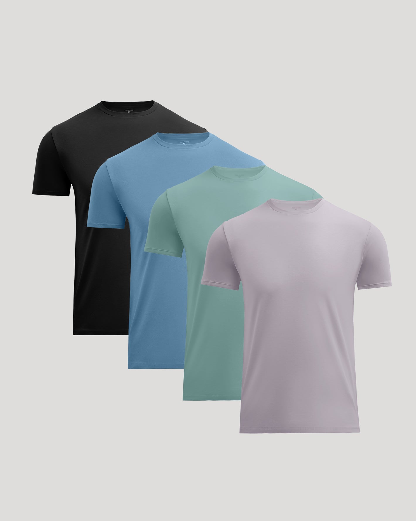 Four short-sleeve crew-neck t-shirts in black, light blue, mint green, and light purple, arranged in a diagonal stack on a solid light gray background.