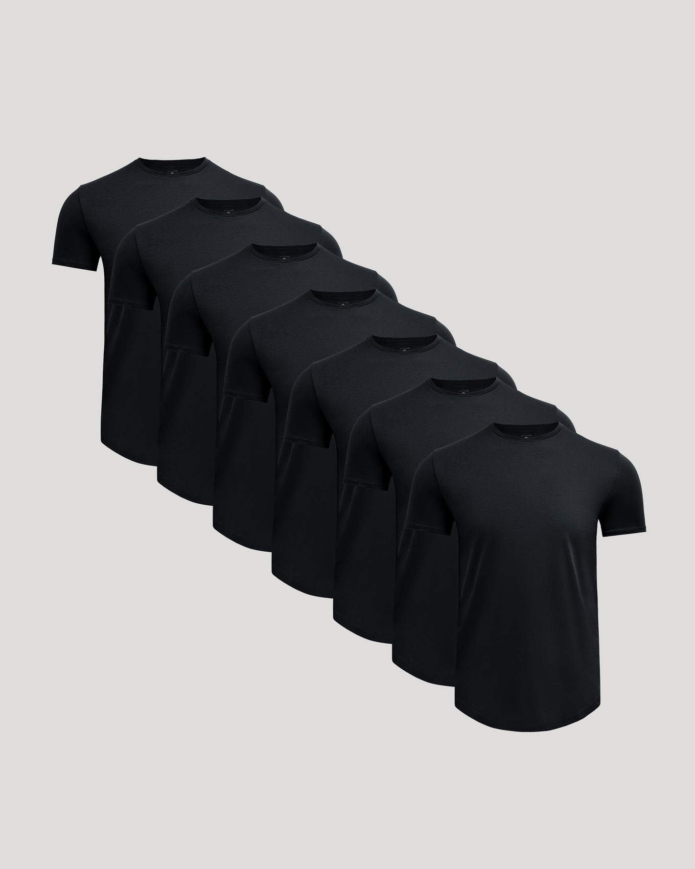 Seven black crew neck t-shirts neatly arranged, showcasing the Pima Cotton Blend Curved Hem Crew 7-Pack as comfortable and stylish men's basics.