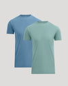 Two short-sleeve crew-neck t-shirts shown on invisible mannequins against a light gray background. The front shirt is a muted sage green, and the shirt behind it is a dusty medium blue.