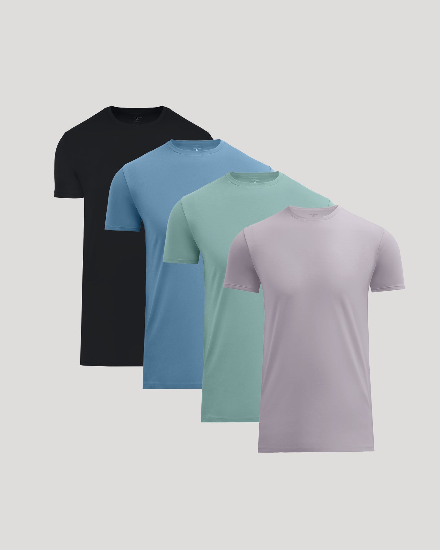 Four short-sleeve crew-neck t-shirts in black, blue, mint green, and light purple, arranged in a diagonal stack on a light gray background.