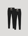 Two black jogger pants with white drawstrings on a light gray background