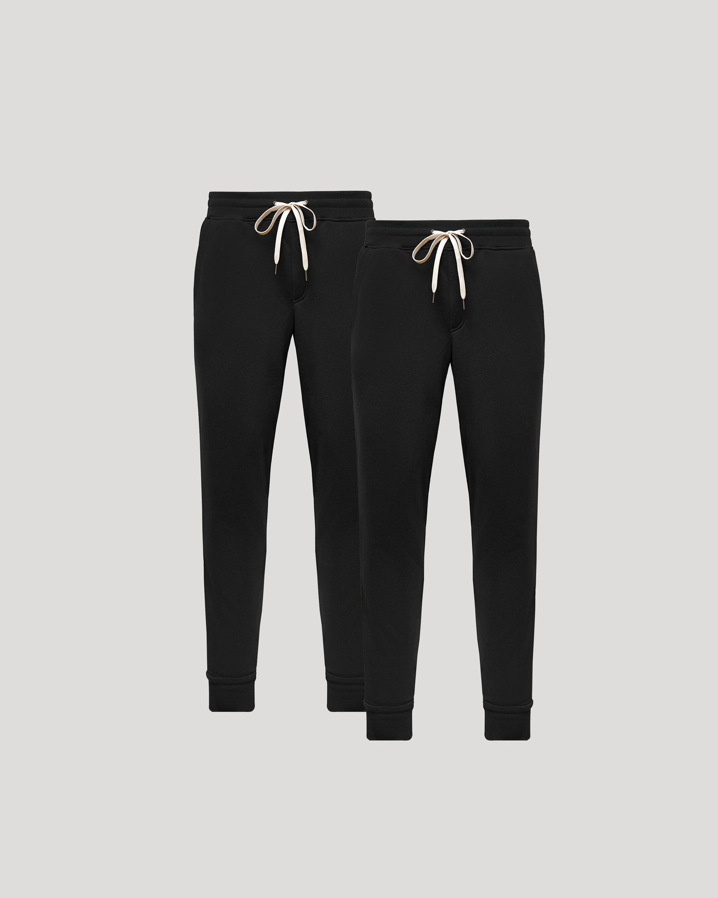 Two black jogger pants with white drawstrings on a light gray background