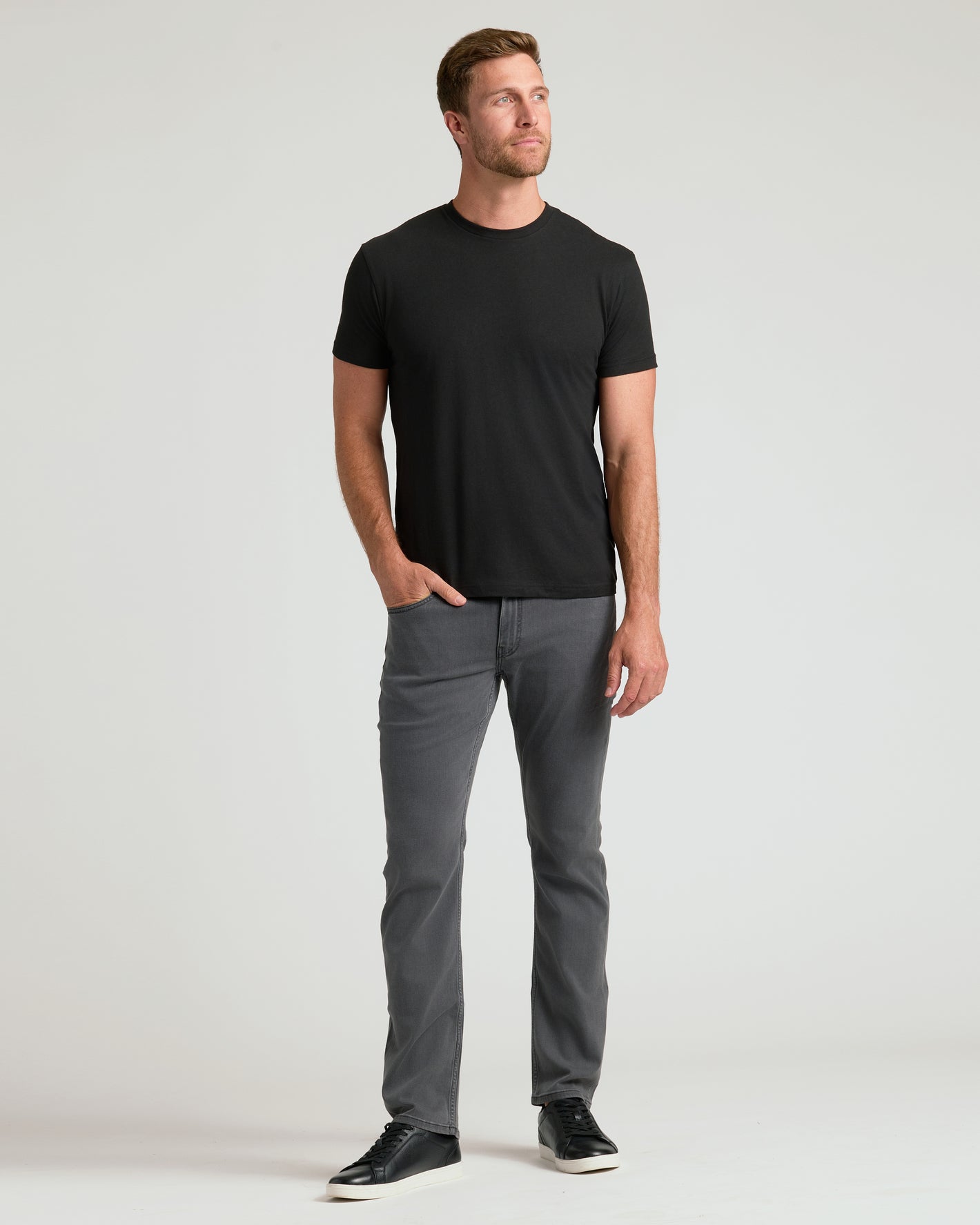 Man wearing a black t-shirt and gray pants on a white background