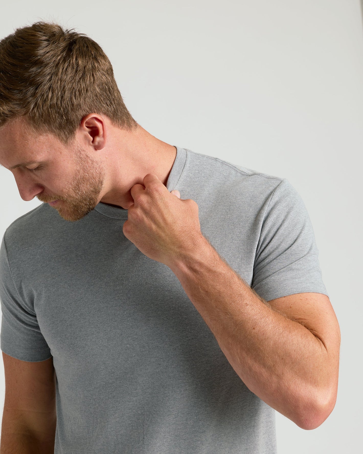 Man wearing Heather Gray Classic Crew Neck T-shirt, tugging collar.
