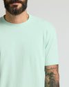 Man in Heather Mist Classic Crew Neck, tattoo visible on forearm.