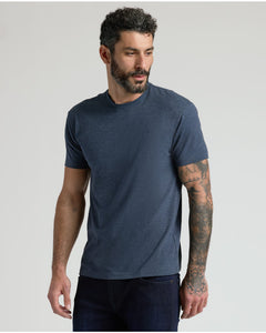 True ClassicA man wearing a short-sleeve crewneck t-shirt in heathered navy blue, paired with dark jeans, photographed against a solid light gray background.