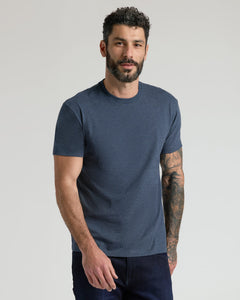 True ClassicA man wearing a dark heather blue crewneck t-shirt and dark jeans, standing against a light gray studio background.