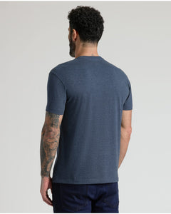 True ClassicA man viewed from behind wearing a heathered slate blue short-sleeve t-shirt and dark navy jeans, standing against a light gray studio background.