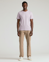 Man wearing a light purple t-shirt and beige pants on a white background