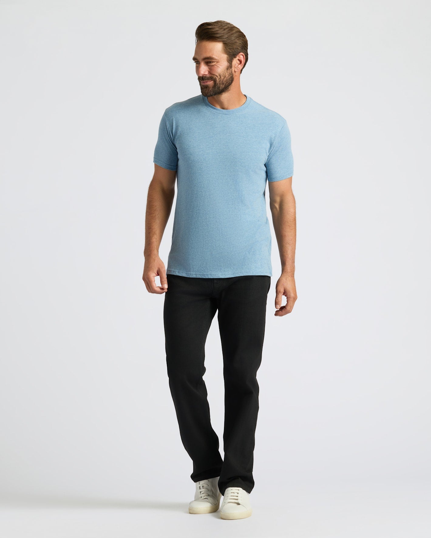 Man wearing a light blue t-shirt and black pants on a white background