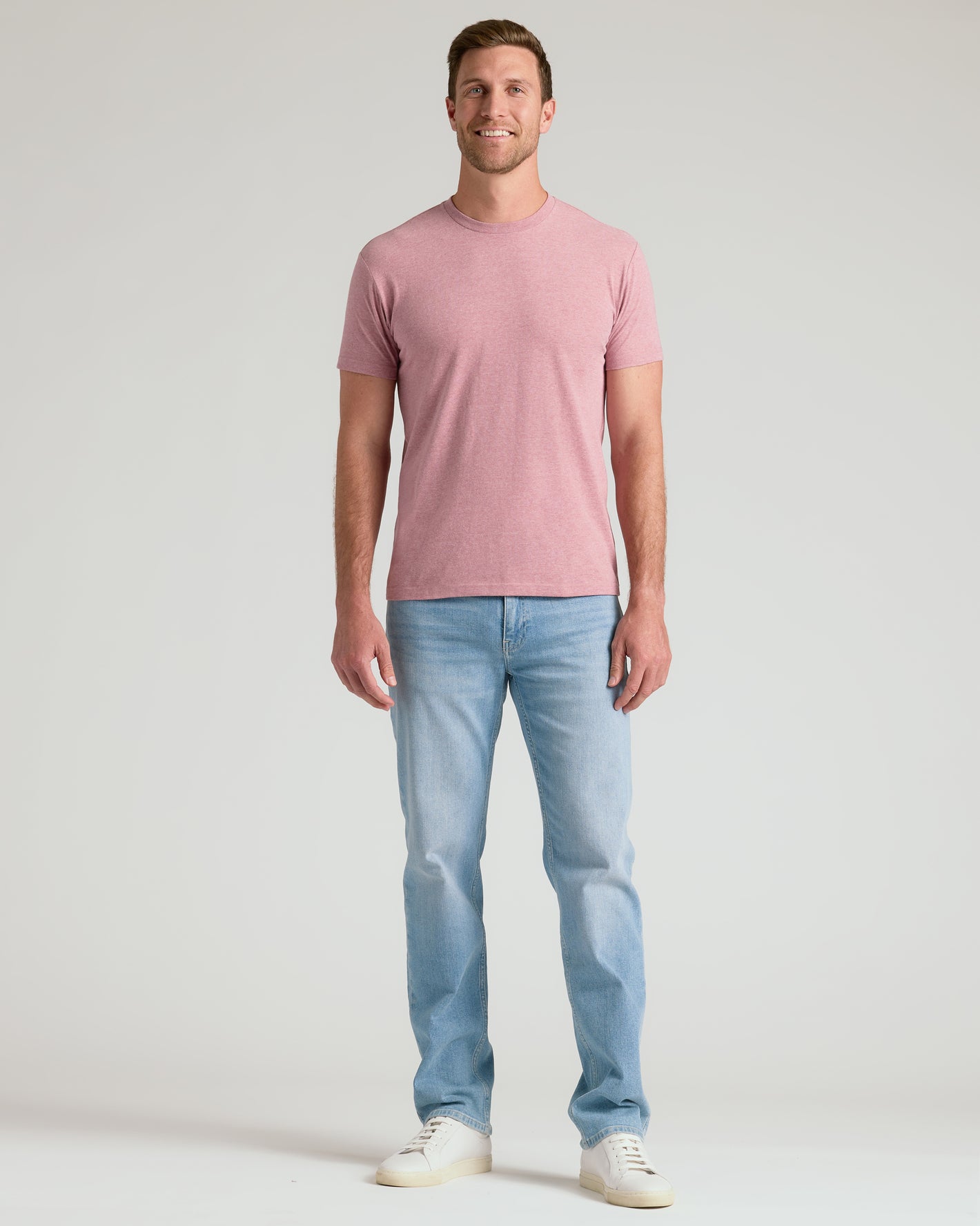 Pink crew neck short sleeve t-shirt with light blue jeans and white sneakers.