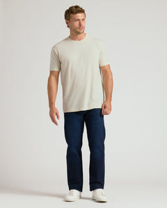 True ClassicMan wearing a beige t-shirt and dark blue jeans on a white background