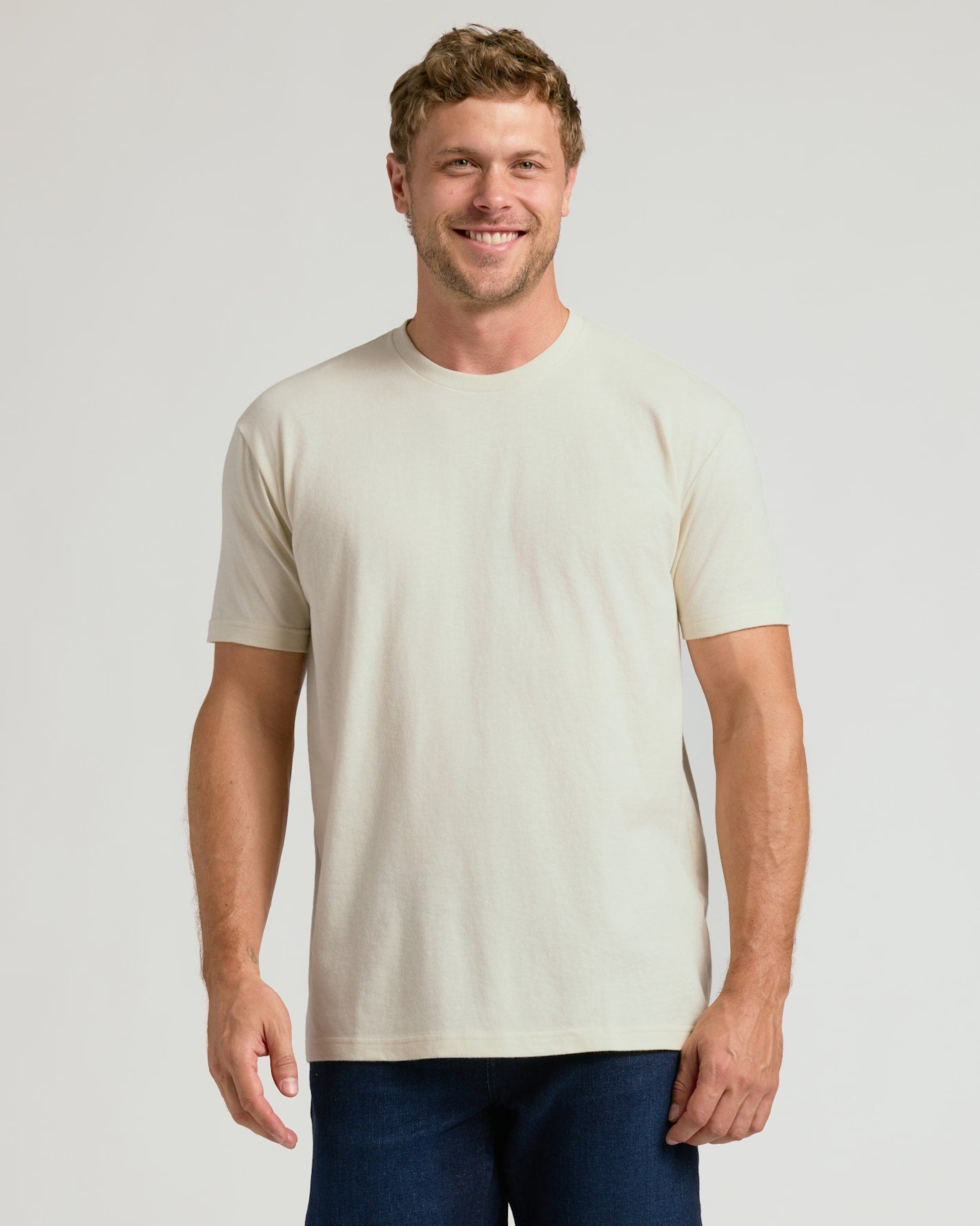 Man wearing a plain beige t-shirt against a light gray background