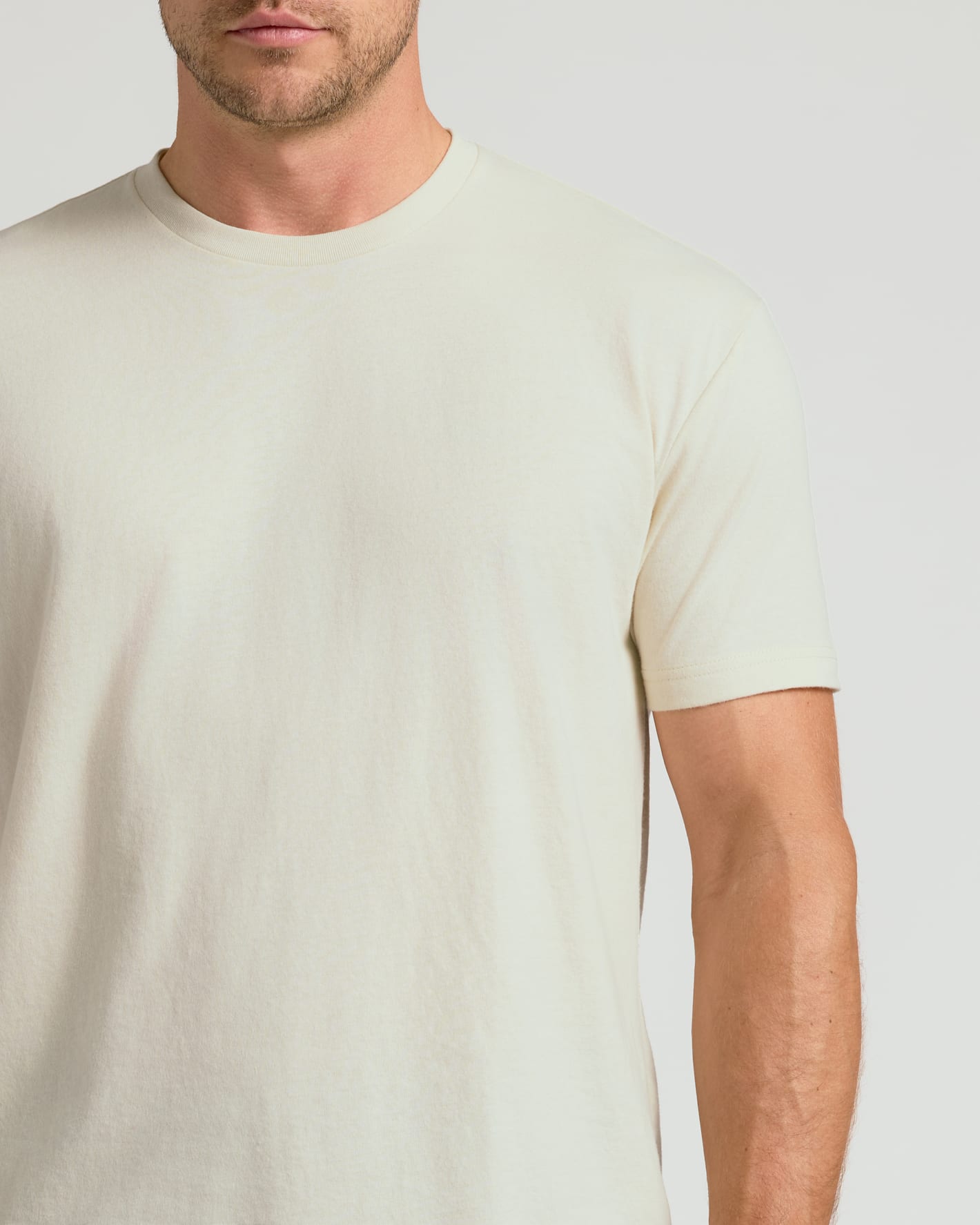 Man wearing a plain light-colored t-shirt against a neutral background