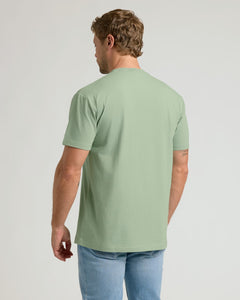True ClassicMan wearing a light green t-shirt and blue jeans on a plain background