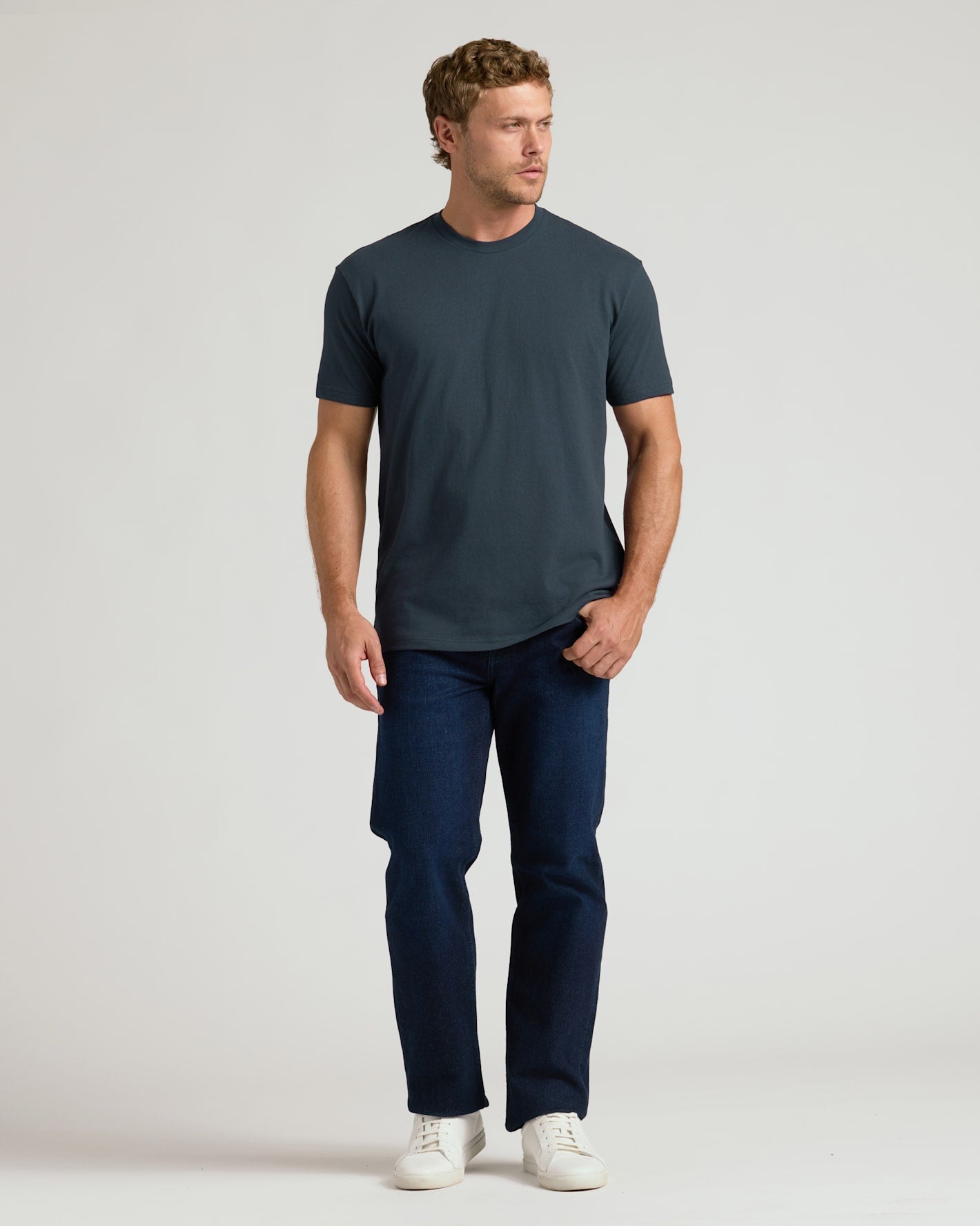 Man wearing a dark blue t-shirt and jeans on a white background