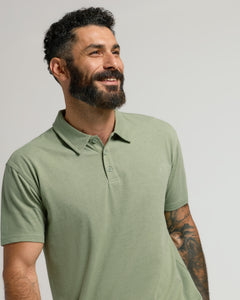True ClassicMan in Dark Heather Bay Green Classic Polo, smiling with tattoo visible.