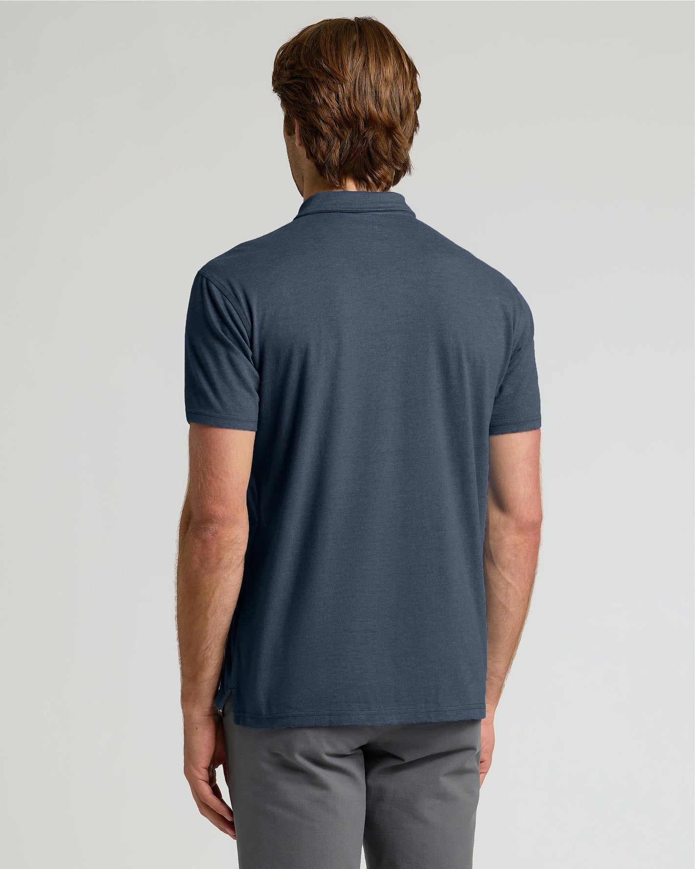 Man wearing a blue polo shirt on a light gray background