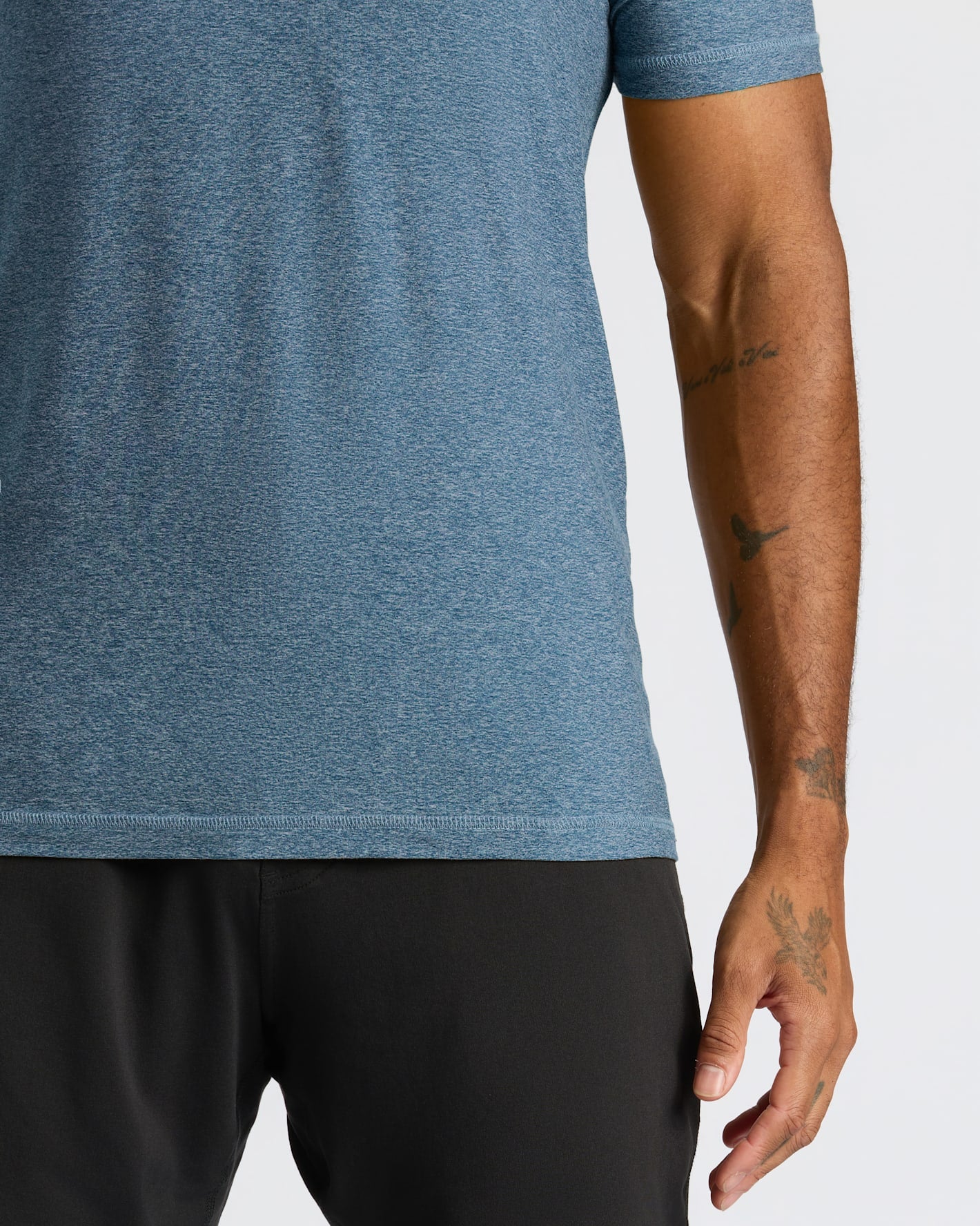 Close-up of a man wearing a Baltic Active Crew Neck Tee in blue heather fabric, paired with black shorts, showcasing the fit and texture of the men's basics shirt.