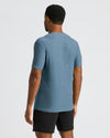 Man wearing a blue Baltic Active Crew Neck Tee standing with back facing the camera, paired with black shorts against a plain light background.