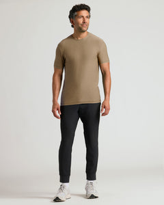 True ClassicMan wearing a Driftwood Active Crew Neck Tee paired with black jogger pants and white sneakers, standing against a plain light background with a relaxed posture.