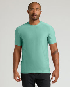 True ClassicA man wearing a short-sleeve crewneck t-shirt in a solid mint green color, paired with black pants, standing against a light gray studio background.
