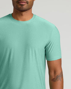 True ClassicA close-up of a man wearing a short-sleeve crewneck t-shirt in a heathered mint green color, shown from the chin down against a light gray background.