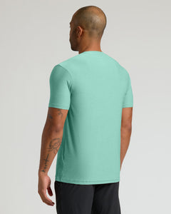 True ClassicA man viewed from the back wearing a short-sleeve crewneck t-shirt in a heathered mint green color, paired with black athletic pants, against a light gray studio background.