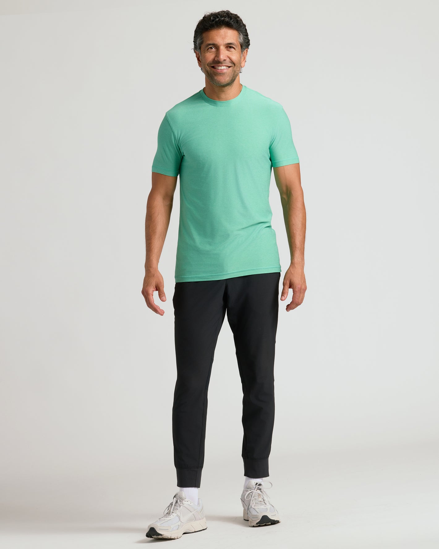 Man wearing Fern Active Crew Neck Tee, slim-fit joggers, and white sneakers.