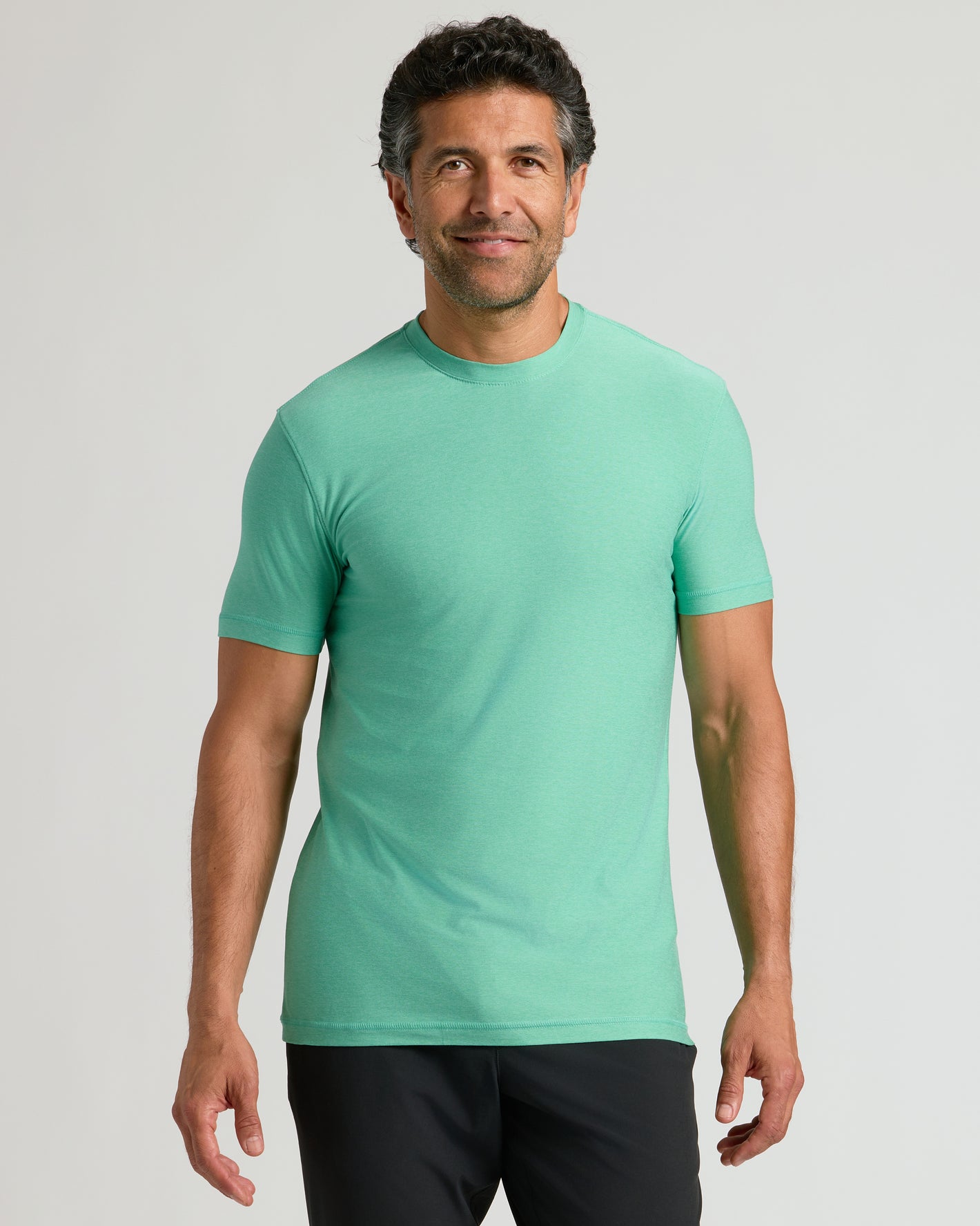 Man wearing Fern Active Crew Neck Tee and dark pants in studio portrait.