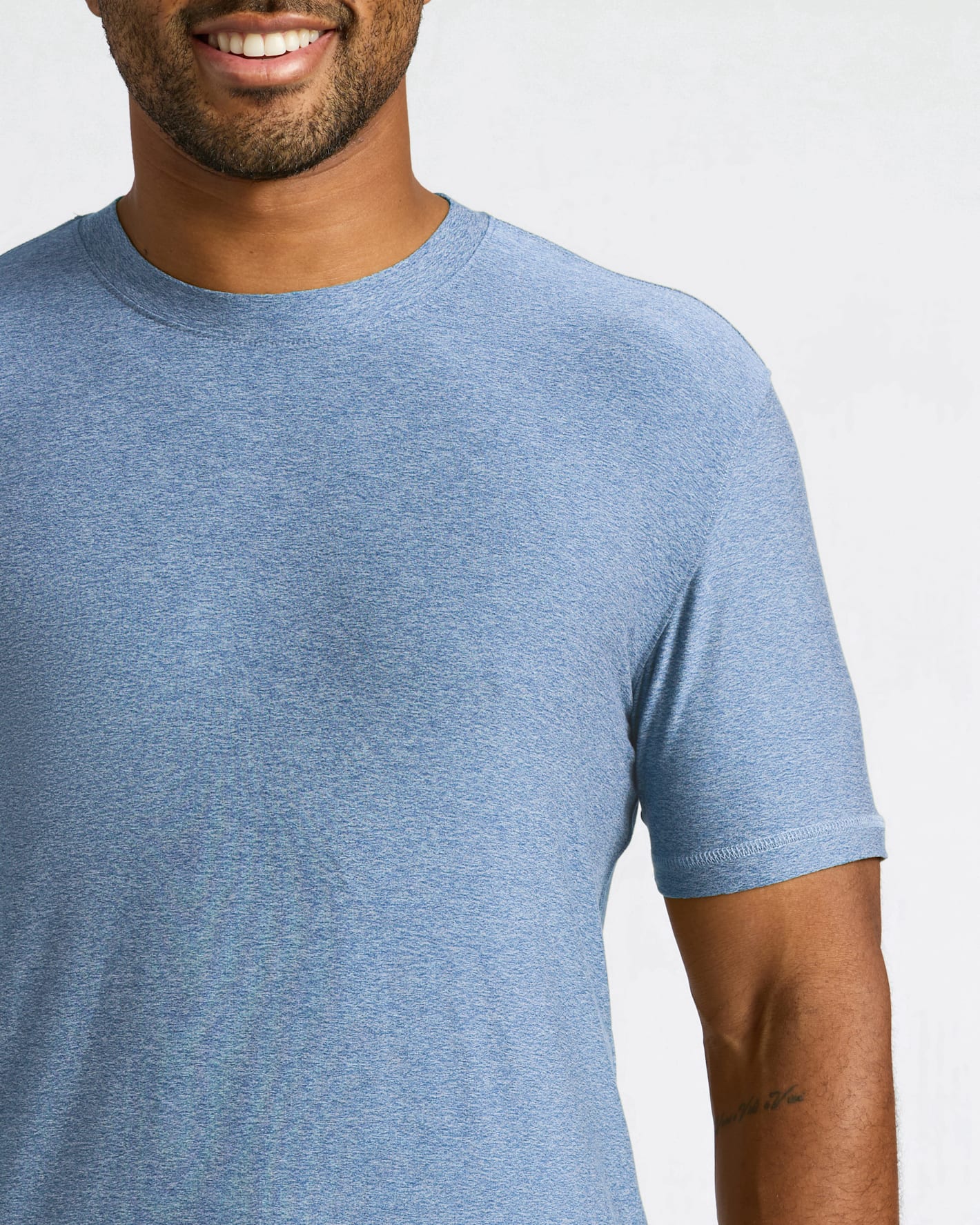 A close-up of a man wearing a heathered blue crew-neck t-shirt against a light gray background.