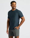 Man wearing a dark green t-shirt and gray shorts on a light gray background
