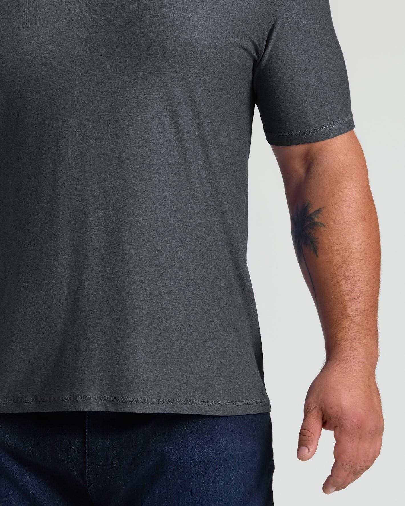 Close-up of a man wearing a charcoal heather gray short sleeve shirt showing the fit and texture of the Charcoal Heather Gray Active Polo 2.0 with a visible tattoo on his forearm.