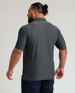 True ClassicMan wearing a charcoal heather gray active polo 2.0 with short sleeves, shown from the back, paired with dark blue jeans in a studio setting
