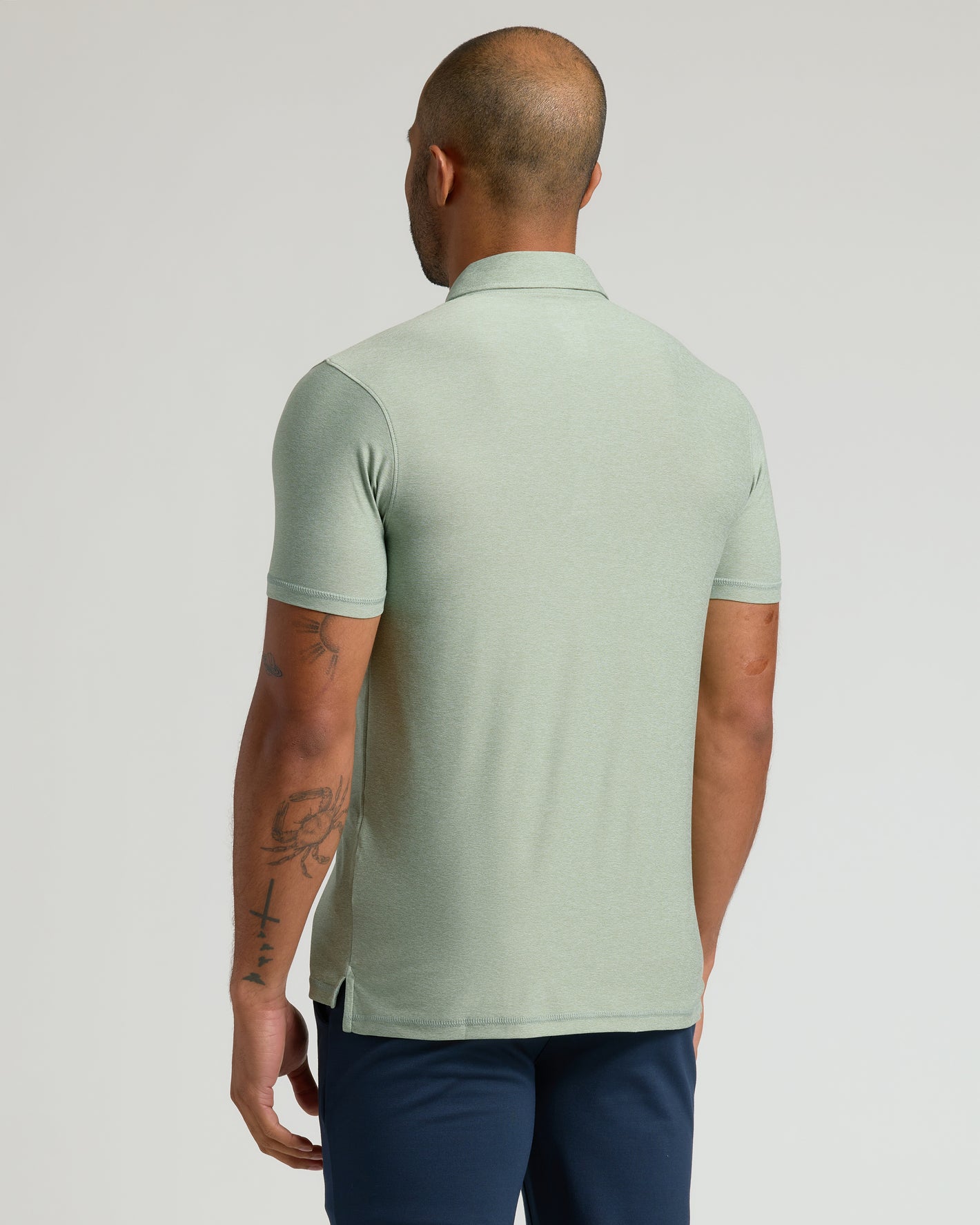 Lichen Active Polo 2.0, back view, showcasing tattoos and side slit.