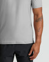 Close-up of a man wearing a Light Heather Gray Active Polo 2.0 paired with black shorts, showcasing the short sleeve and casual fit of this men's basics polo shirt.
