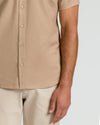 Dusty Taupe Short Sleeve Linen Shirt worn with light pants.