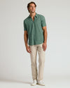 Man modeling Moss Short Sleeve Linen Shirt with beige trousers and white sneakers.