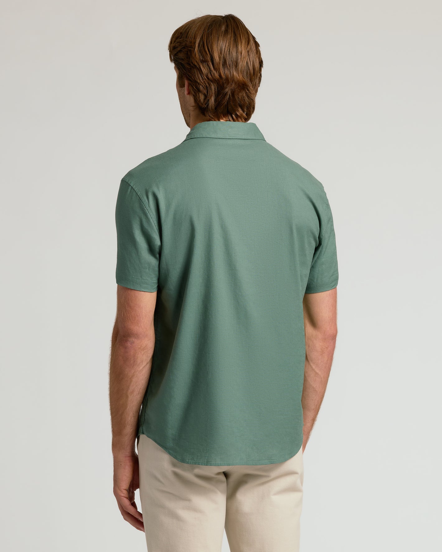 Back view of Moss Short Sleeve Linen Shirt worn with beige trousers.