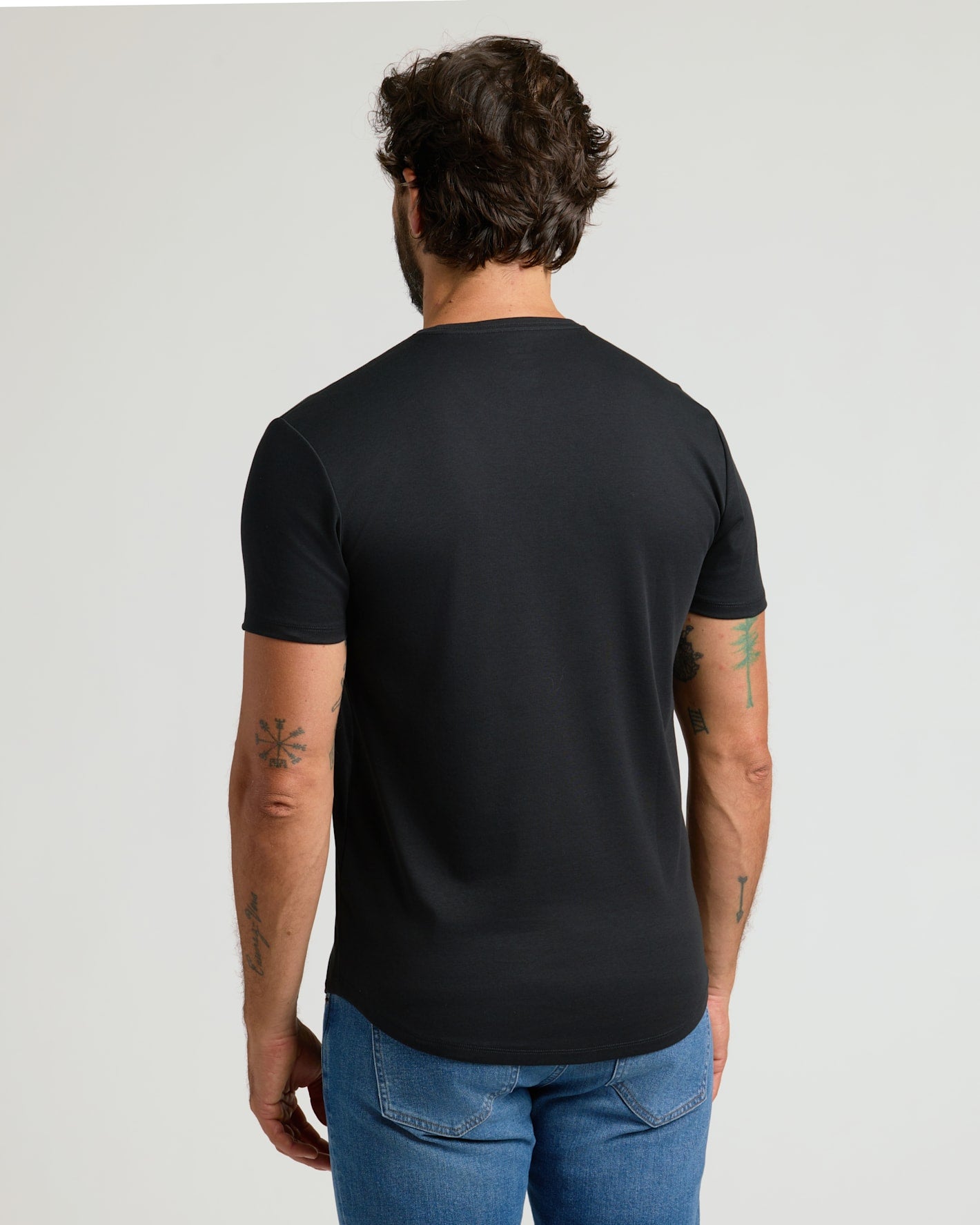 Man wearing a black Pima Cotton Blend Curved Hem Crew 7-Pack t-shirt shown from the back, paired with blue jeans, highlighting the curved hem design and comfortable fit.