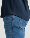 Close-up side view of a person wearing the Navy Pima Cotton Blend Curved Hem Crew paired with blue jeans, highlighting the curved hem detail on a men's basics top.