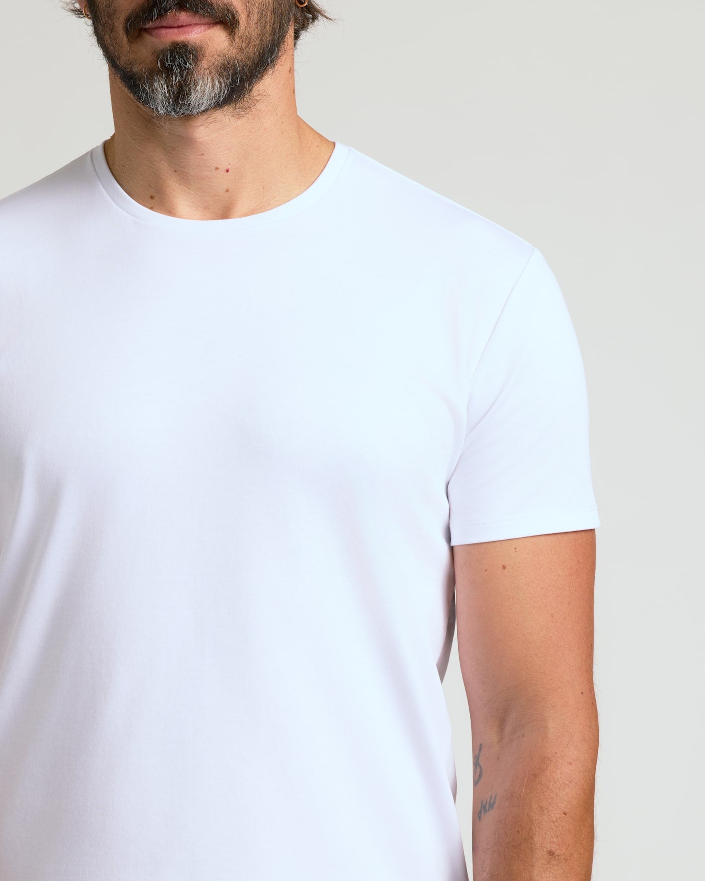 Close-up of a man wearing a white Pima Cotton Blend Curved Hem Crew 7-Pack t-shirt, showcasing the soft fabric and classic crew neck fit, a men's basics essential.