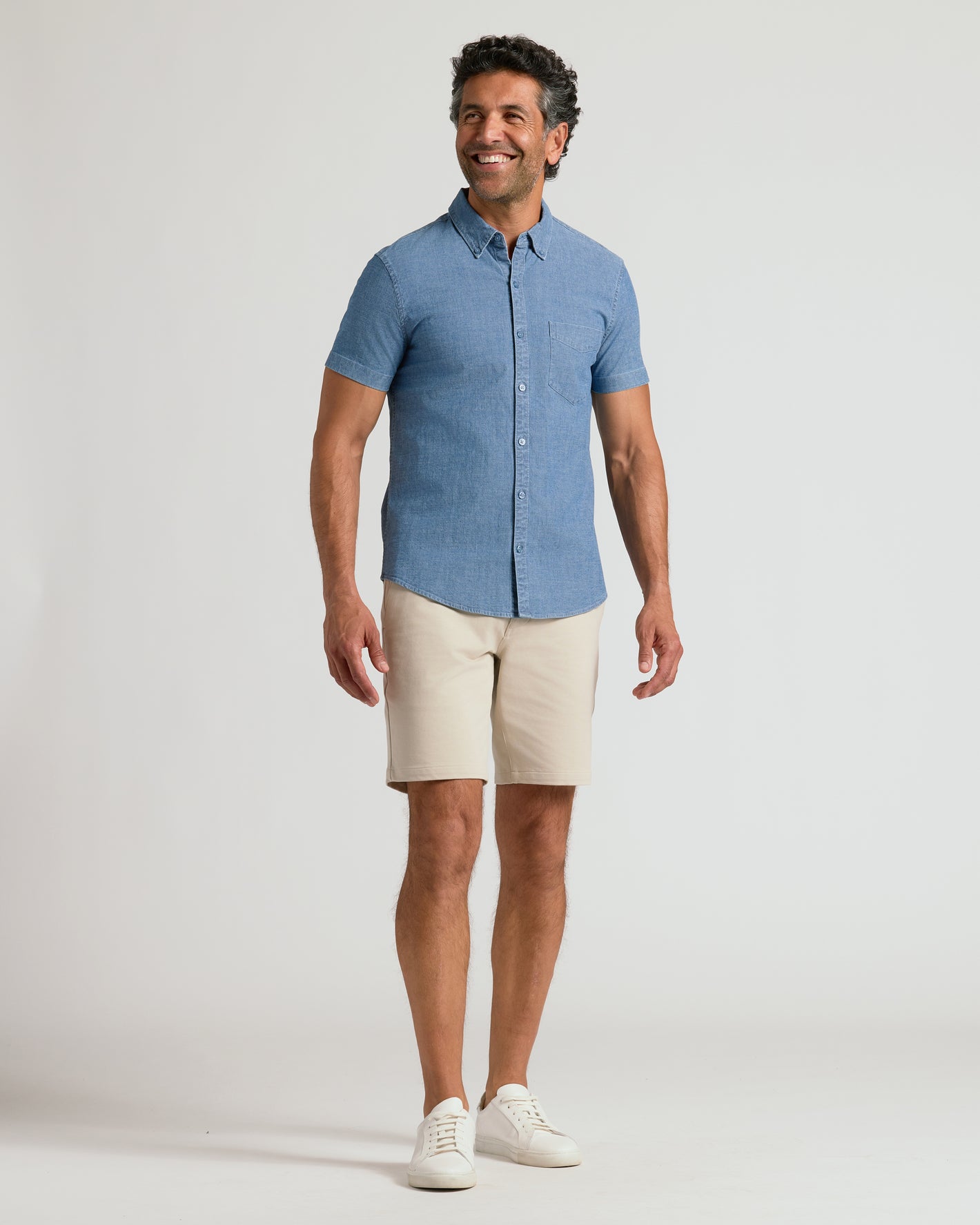 Man wearing Light Indigo Wash Short Sleeve Stretch Chambray Shirt, beige shorts.