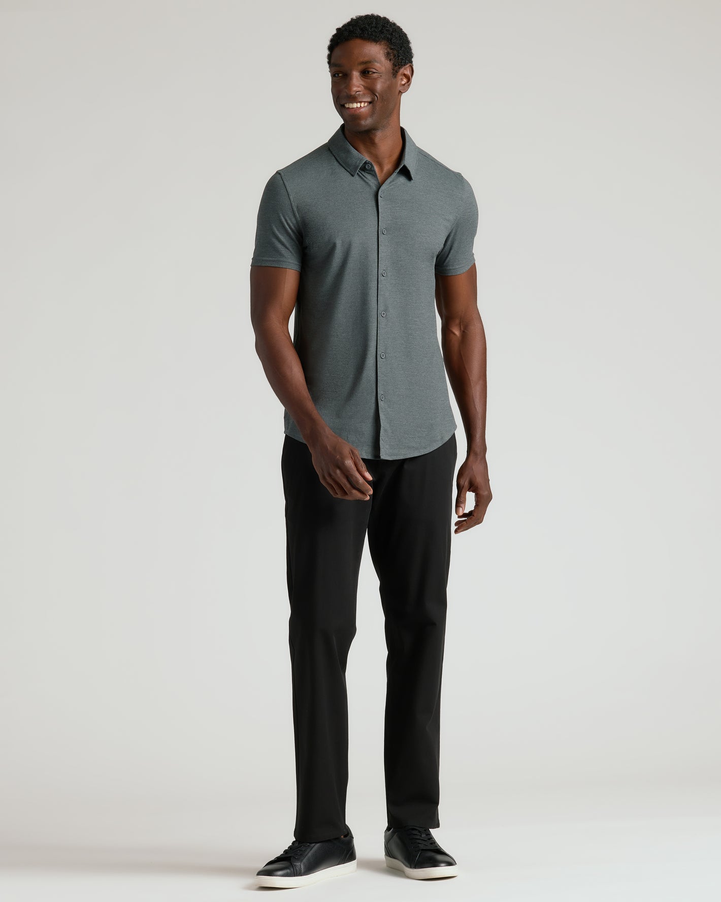 Man wearing Charcoal Heather Gray Short Sleeve Comfort Knit Shirt, black pants, sneakers.