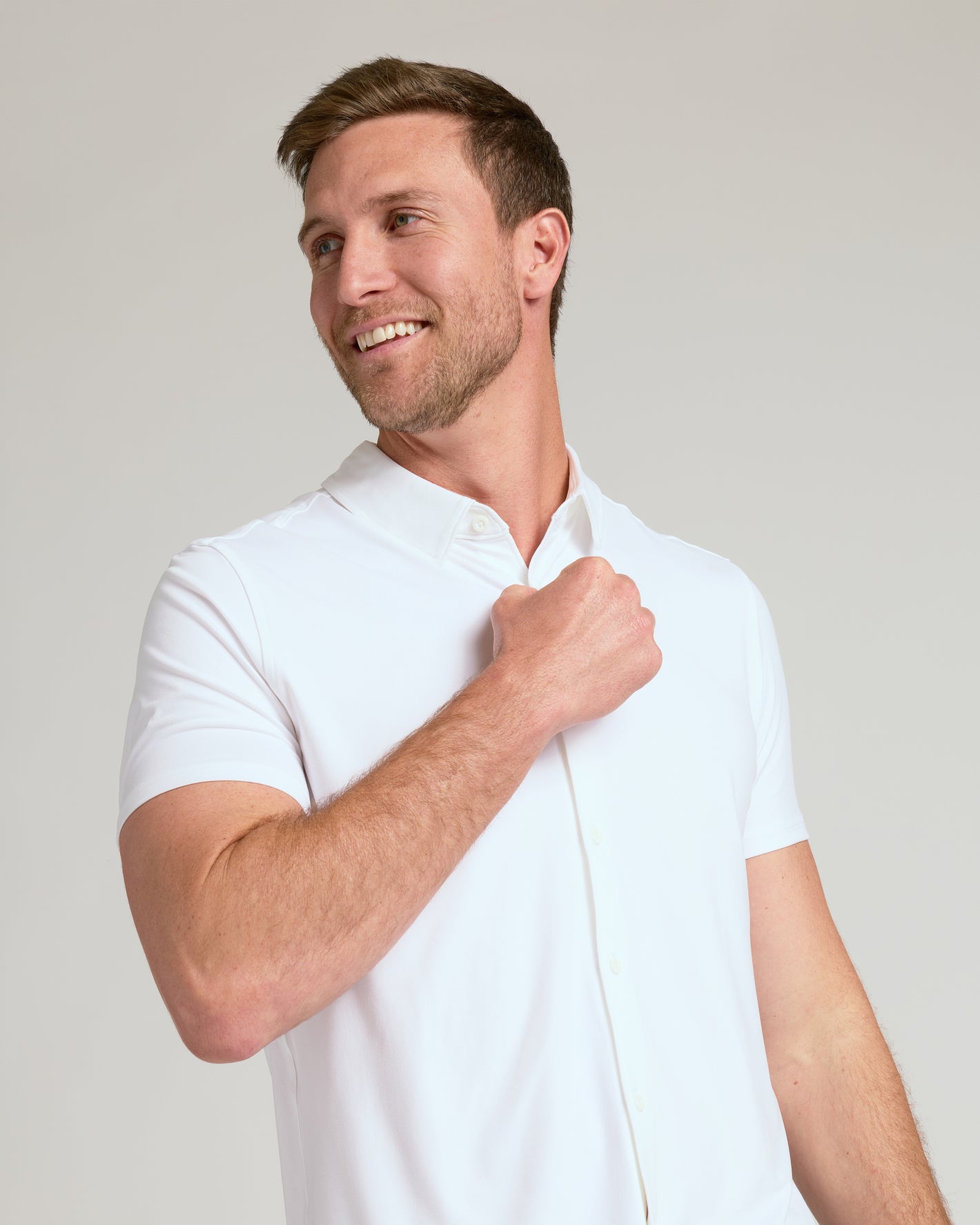 Man wearing White Short Sleeve Comfort Knit Shirt, adjusting front.