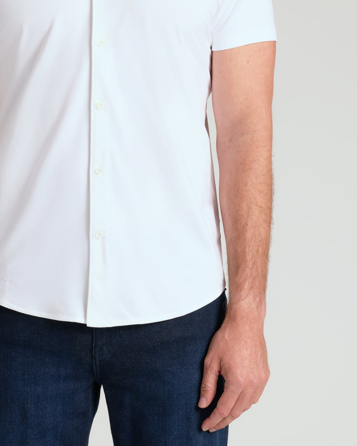 White Short Sleeve Comfort Knit Shirt with dark blue jeans, right arm visible.