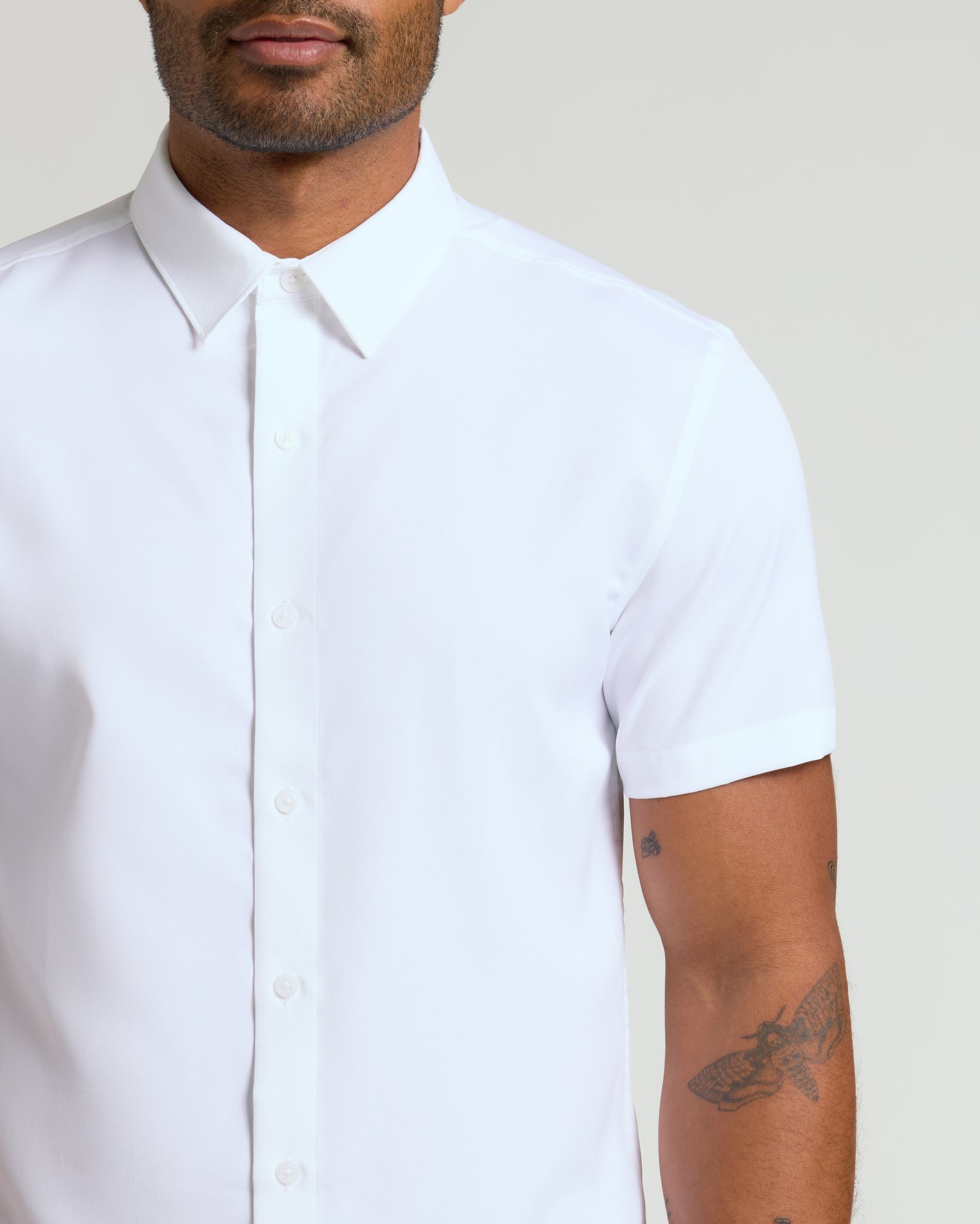 Person wearing All White Short Sleeve Performance Dress Shirt, showing tattoos.