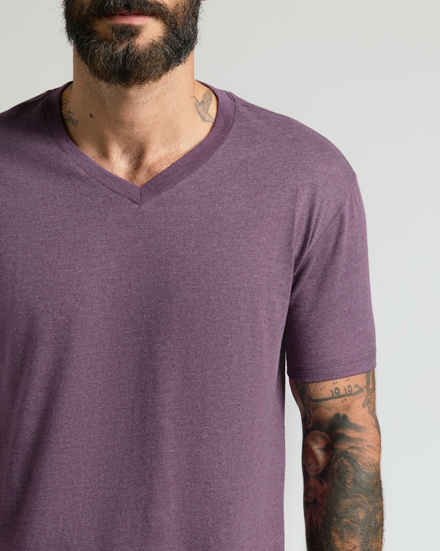 Man wearing Dark Heather Plum Classic V-Neck, showcasing tattoos.